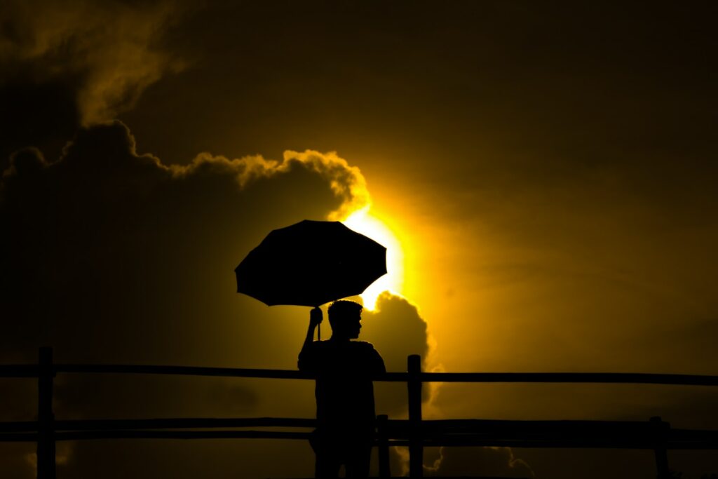 a person holding an umbrella in front of the sun